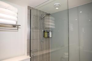 a bathroom with a shower with a glass door at Holiday Inn Brighton Seafront by IHG in Brighton & Hove