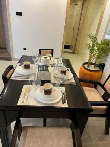 a black table with plates and cups and wine glasses at Urban Oasis 2BR in Nairobi
