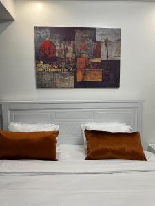 a bed with two pillows and a painting on the wall at Urban Oasis 2BR in Nairobi