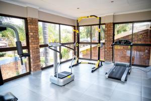 a gym with three treadmills in a room with windows at Boksburg Boutique Hotel in Boksburg