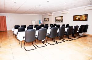 a conference room with a long table and black chairs at Boksburg Boutique Hotel in Boksburg