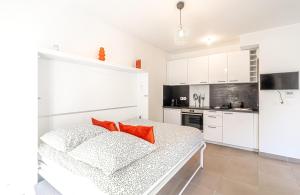 een keuken met witte kasten en rode kussens op een bed bij Charming Studio with Parking near Monaco in Beausoleil