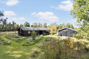 two black buildings in a field with trees at EchoBay nr 2 - child-friendly house close to the beach in Jerup