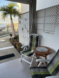 un patio con sillas, una mesa y una palmera en Apartman VERA - Beautiful Sunshine And Sea View, en Puerto Rico de Gran Canaria