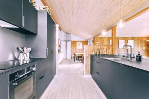 a kitchen with black cabinets and a wooden ceiling at EchoBay nr 2 - child-friendly house close to the beach in Jerup