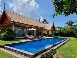 a house with a swimming pool in front of a house at MJ Beautiful sunset beach house in Ban Na We
