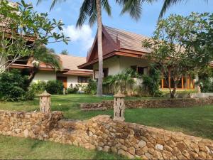 a house with a stone wall in front of it at MJ Beautiful sunset beach house in Ban Na We