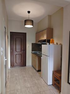 a kitchen with a white refrigerator and a brown door at House Anna Sarti in Sarti