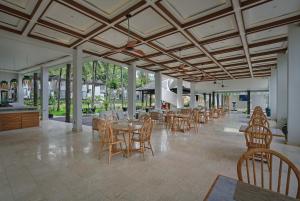 una sala da pranzo con tavoli, sedie e finestre di The Sebali Penida Beach Resort a Nusa Penida