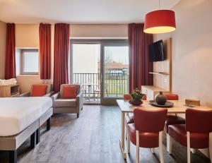 a hotel room with a bed and a table and chairs at Holiday Suites Westende - Middelkerke in Middelkerke