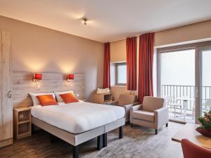 a hotel room with a bed and a chair at Holiday Suites Westende - Middelkerke in Middelkerke +108 photos
