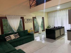 a living room with a green couch and a table at Casa Aconchego da Serra - Pacoti in Pacoti