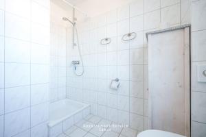 a white bathroom with a shower and a toilet at Hafenresidenz W16 in Laboe +20 photos