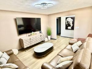 a living room with a couch and a flat screen tv at Delightful 3 Bd Home with King size bed, hot tub, playground! in Indianapolis