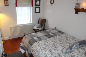 ein Schlafzimmer mit einem Bett, einem Stuhl und einem Fenster in der Unterkunft Tigín Tuí in Carndonagh