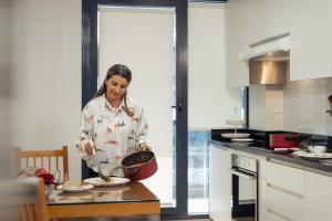 a woman standing in a kitchen holding a pot at Golden Sands Suites in Dubai