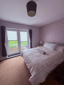 a bedroom with a bed and a large window at Beautiful park view town house in Wigan