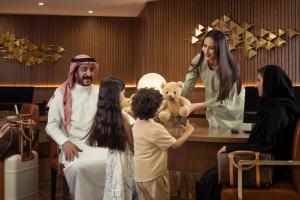 a nun holding a teddy bear with a group of people at Golden Sands Suites in Dubai
