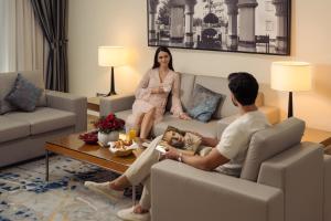 a man and a woman sitting in a living room at Golden Sands Suites in Dubai