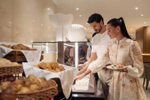 a man and a woman in a kitchen preparing food at Golden Sands Suites in Dubai