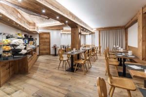 a restaurant with wooden floors and tables and chairs at Hotel Olimpia in Cortina dʼAmpezzo