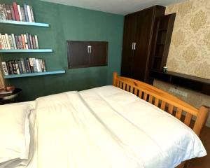 a bedroom with a white bed with a book shelf at April Fair Duplex Apartment Guagnzhou South Railway Station Min Jie Branch in Guangzhou