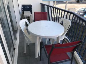 Una mesa blanca y dos sillas en un balcón. en Appartement cosy mer, en Le Grau-du-Roi