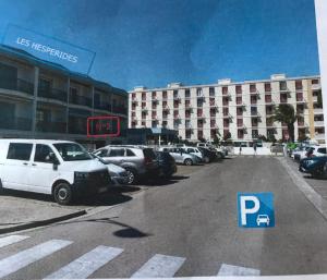 Un estacionamiento con autos estacionados frente a un hotel. en Appartement cosy mer, en Le Grau-du-Roi