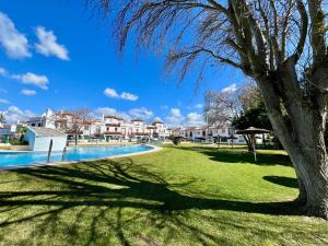a tree in a park with a swimming pool at Paradise Vista in Poblado de Sancti Petri