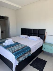a bedroom with a large bed with a black headboard at Refúgio na Praia Casa Confortável e Acolhedora in São Francisco do Sul
