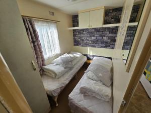 a small room with two beds and a window at Ingoldmells -Caravan- Sleeps 6 - Seaside - Parking in Skegness