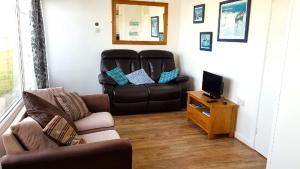 a living room with a leather chair and a television at Chalet 151, Perran Sands in Perranporth