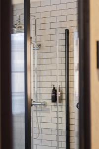 a shower in a bathroom with a white brick wall at Letoh Letoh Bilbao in Bilbao