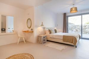 a bedroom with a bed and a mirror and a chair at Villa Infinium TWO, Sunset views 10' from Mykonos town! in Agios Stefanos +25 photos