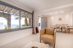 a living room with a chair and a table at Villa Infinium TWO, Sunset views 10' from Mykonos town! in Agios Stefanos