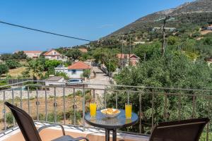a table with two glasses of orange juice on a balcony at Villa Ourania near Myrtos in Divarata