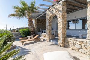 a patio with a wooden bench and a stone wall at Villa Infinium TWO, Sunset views 10' from Mykonos town! in Agios Stefanos