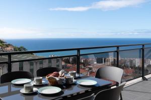 a table on a balcony with a view of the ocean at Amparo II by An Island Apart in Funchal