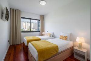two beds in a hotel room with a window at Amparo II by An Island Apart in Funchal