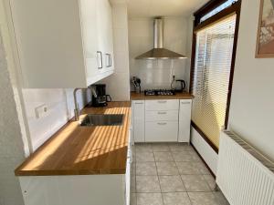 a small kitchen with white cabinets and a sink at Noordzeehuisje in Sint Maartensvlotbrug +10 photos