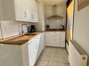 a kitchen with white cabinets and a sink at Noordzeehuisje in Sint Maartensvlotbrug