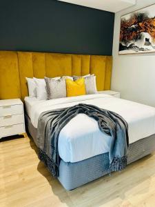 a bedroom with a large bed with yellow pillows at Riamus Luxury Apartment in Midrand