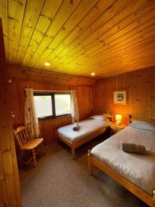 ein Schlafzimmer mit 2 Betten und einem Stuhl in einer Hütte in der Unterkunft 3 Bedroom Lodge Lanteglos 21 in Lanteglos