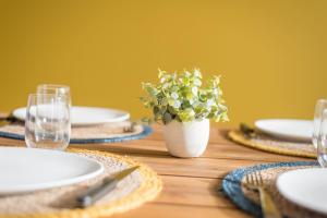 a wooden table with plates and a vase with a plant at BLEU TOUCAN - 700m plage - Parking in Saint-Nazaire
