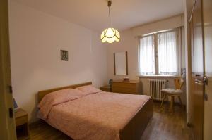 a bedroom with a bed and a chandelier at Accogliente appartamento in Corso Italia in Cortina dʼAmpezzo +4 photos