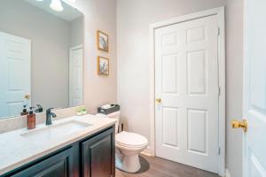 a bathroom with a toilet and a sink and a mirror at Full House HotTub Mins to UCF in Bithlo +25 photos