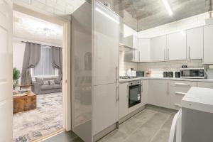 eine Küche mit weißen Schränken und ein Wohnzimmer in der Unterkunft Brierfield Cottage in Brierfield