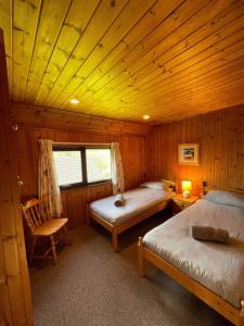 ein Schlafzimmer mit 2 Betten und einem Stuhl in einer Hütte in der Unterkunft 3 Bedroom Lodge Lanteglos 21 in Lanteglos
