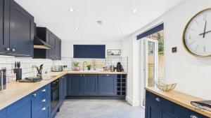 a kitchen with blue cabinets and a large clock on the wall at Simeon Sands Coastal Escape in Ryde