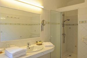 a bathroom with a sink and a shower with a mirror at Hôtel Palombaggia in Porto-Vecchio